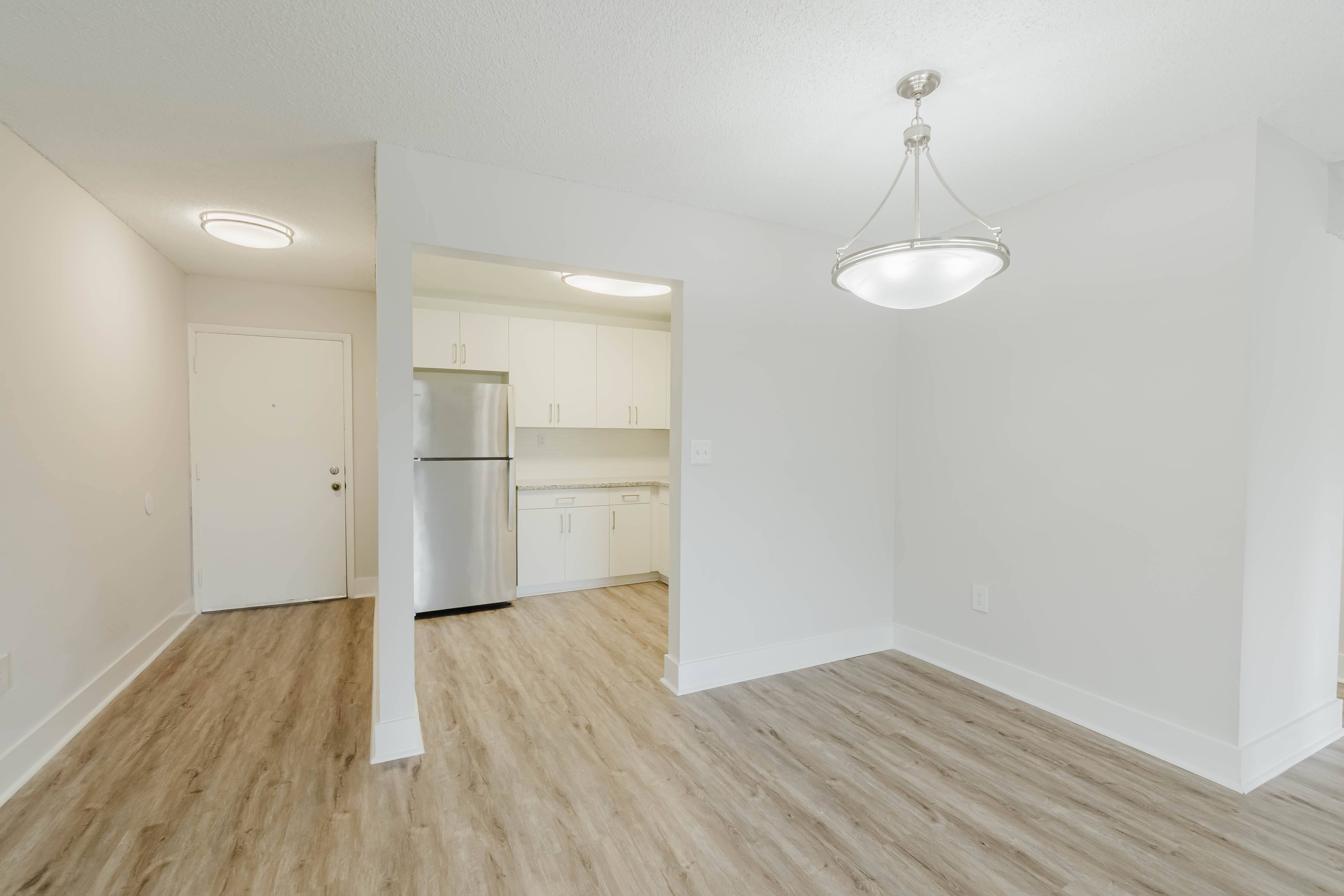 A kitchen with white cabinets and a fridge.